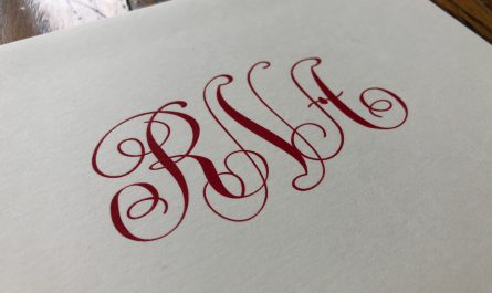 This is an image of a monogram on a folded note. The lettering is printed in red ink and it's on white paper